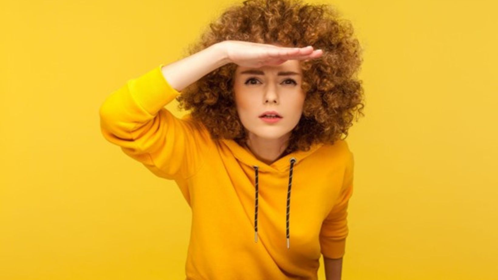 woman looking for someone yellow background