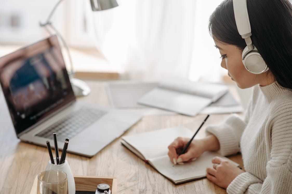 Free A Woman in White Sweater Writing on White Paper Stock Photo